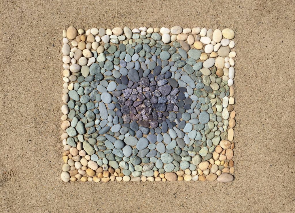 Image of painted rocks in a filled out square creating concentric circles inside, from light outside to dark inside.